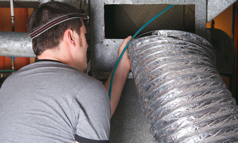 man cleaning an AC’s air duct