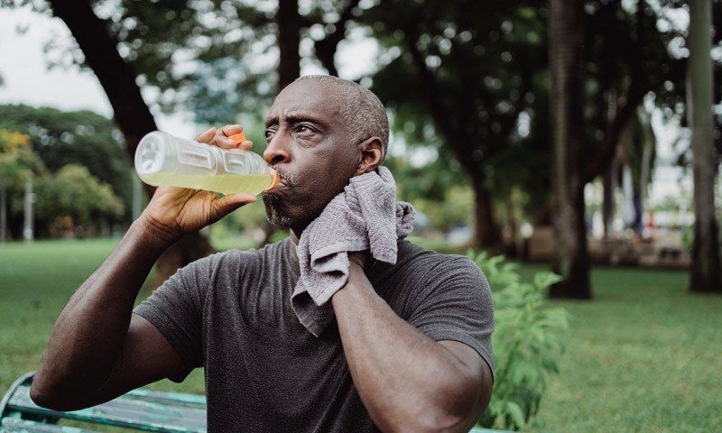 man hydrating and wiping away sweat