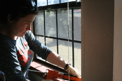 woman caulking her window